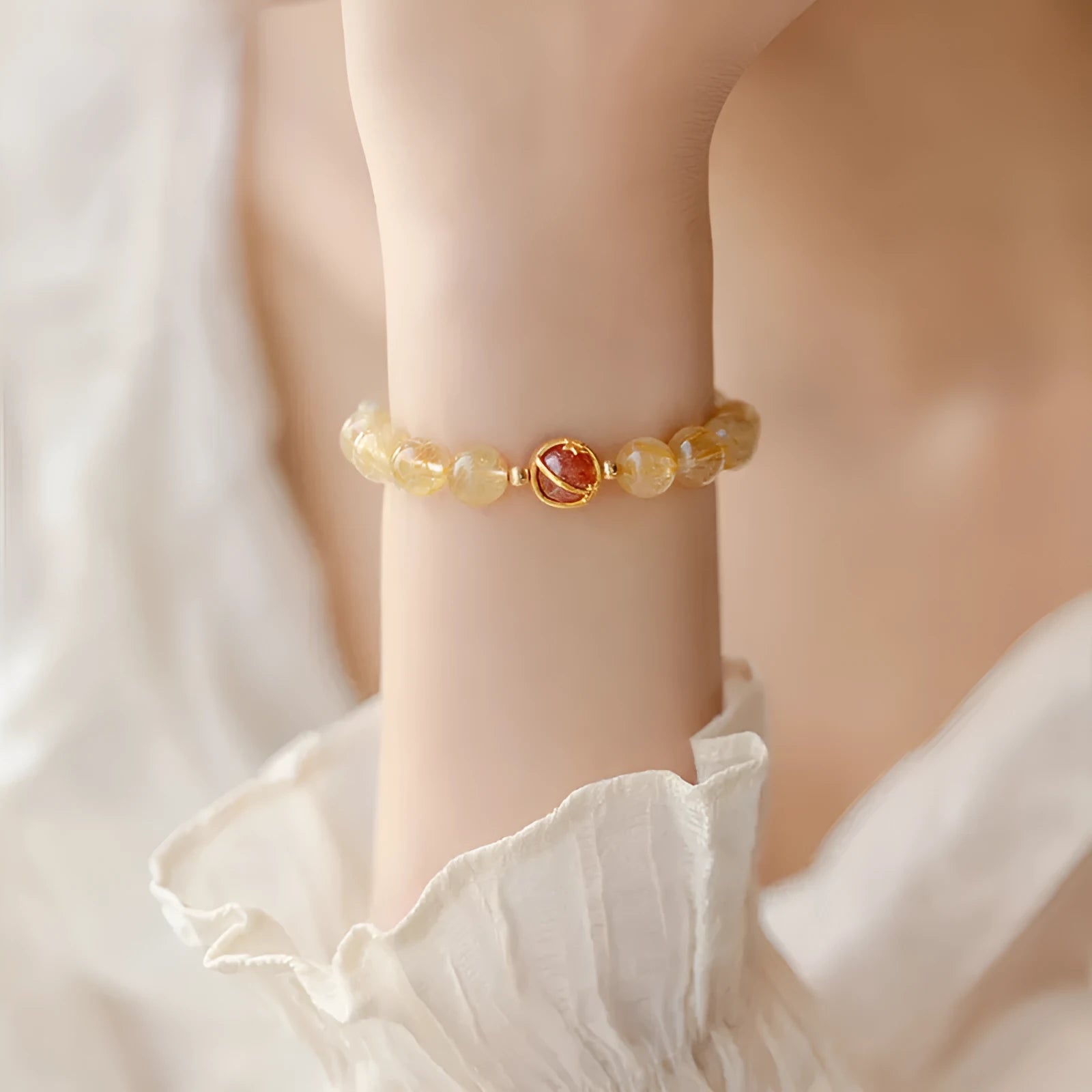 Citrine gold rutilated quartz crystal bracelet with diamond-cut beads on a wrist.