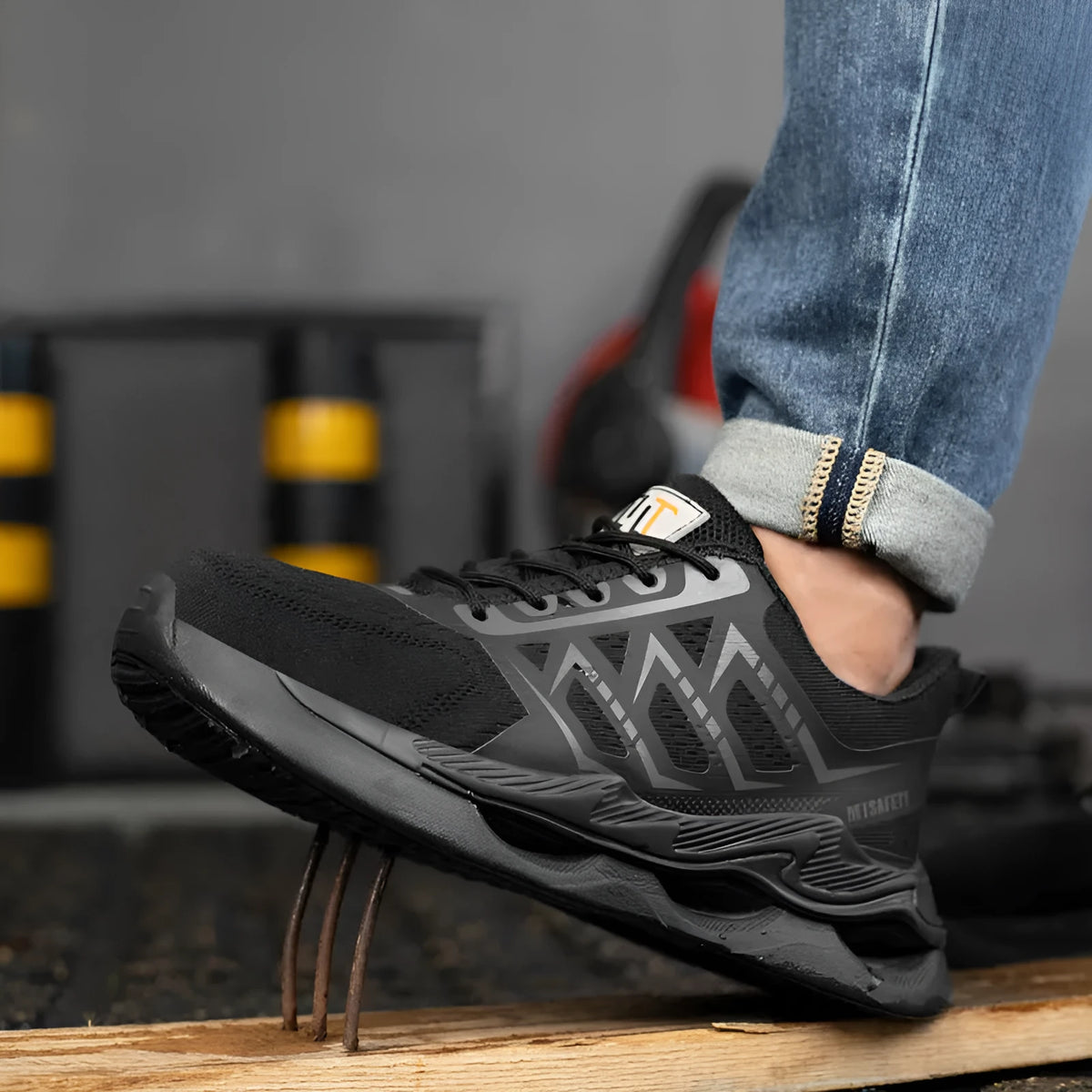 Black steel toe cap safety shoes with flat knitted uppers and rubber soles on a work surface