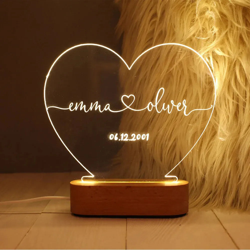 Custom transparent acrylic night light with engraved names and date, lit by an LED base on a table.