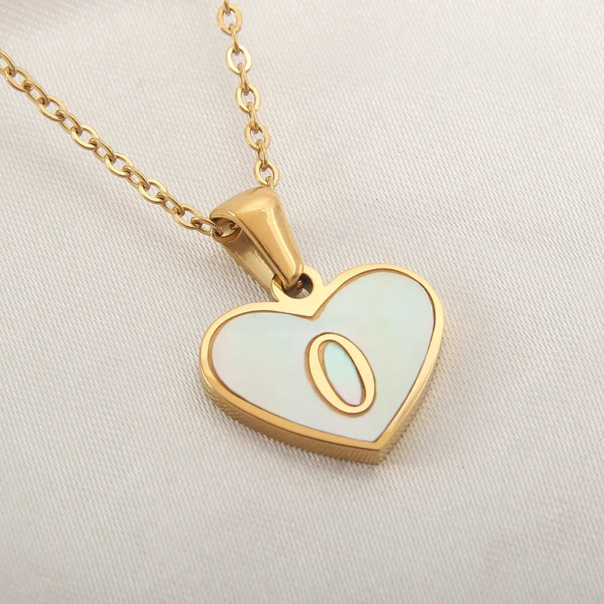 Gold-plated heart necklace with white shell pendant showing initial engraving on stainless steel chain