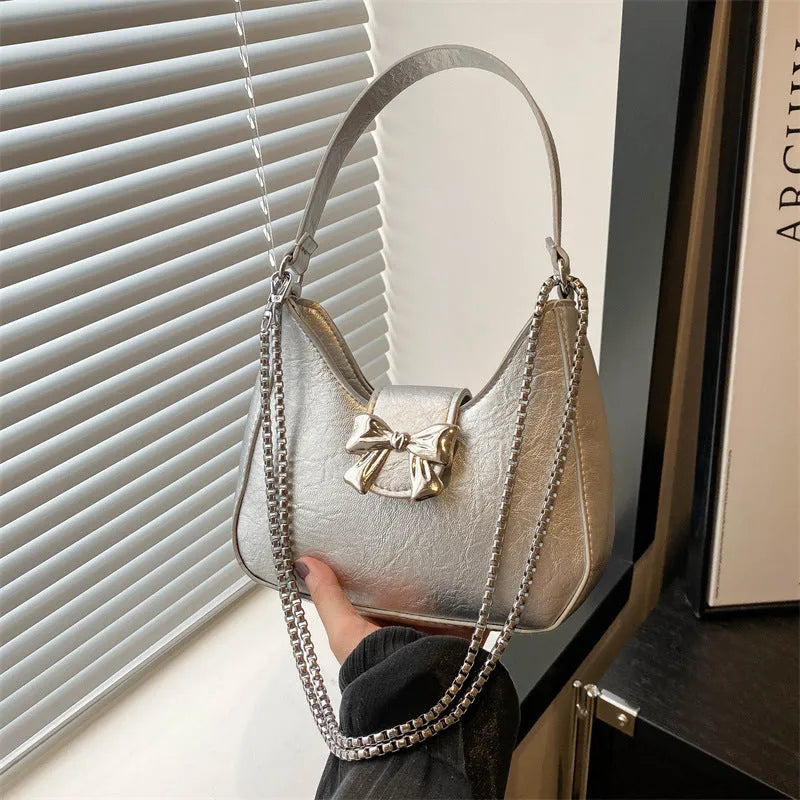 Bow underarm bag in textured PU with one-shoulder strap, dumpling shape and sandwich pocket, shown in black, pink, silver or white