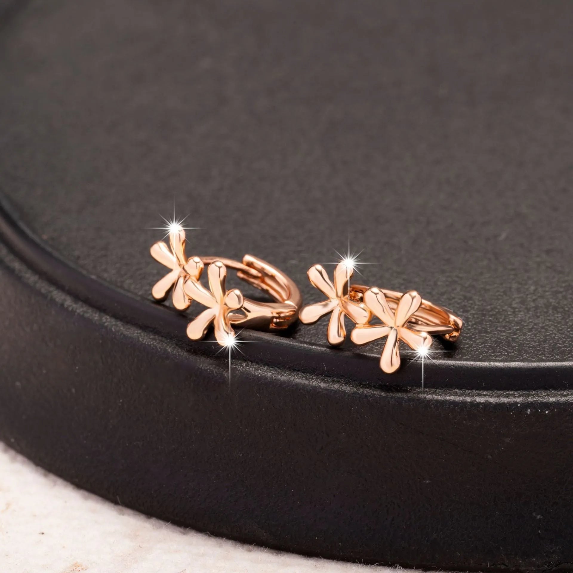 Rose gold waterdrop flower stud earrings with circular floral design on a white background.