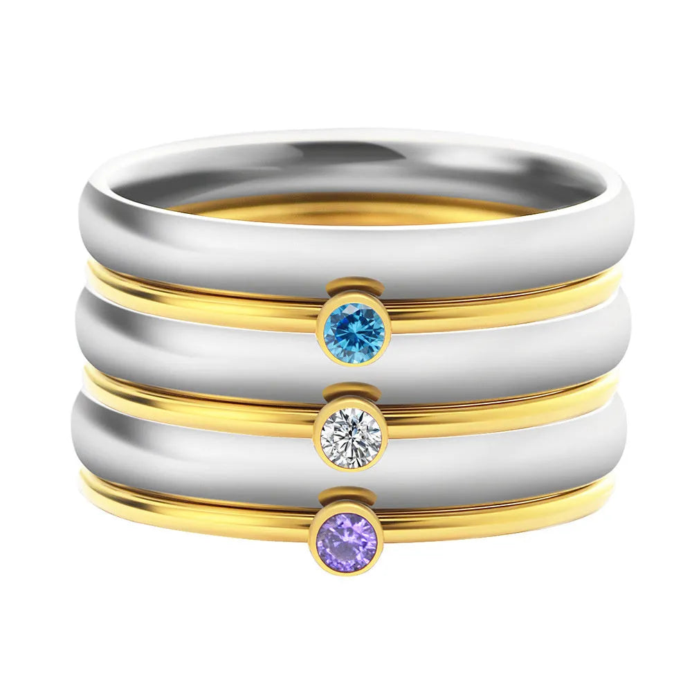A geometric titanium steel ring with a December birthstone and gold-coloured handle on a plain background.