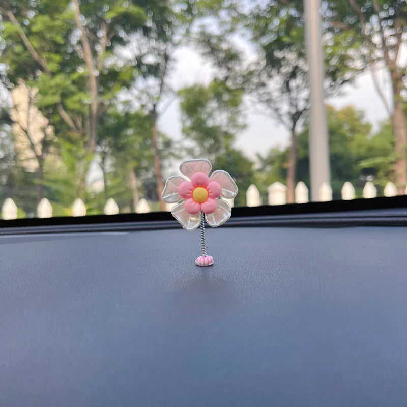 Small colourful plastic swing ornament for car dashboard, shown in blue, green, pink, purple, and yellow.