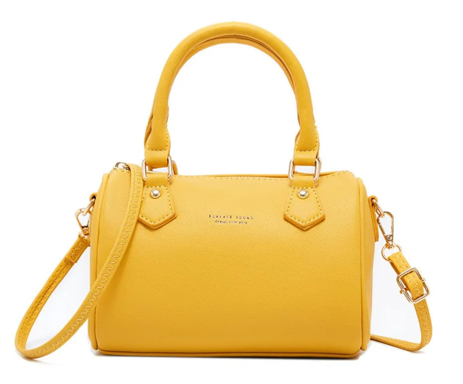 Ladies pillow crossbody bag in PU with zip closure and letter detail, shown in available colours.