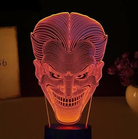 A 3D acrylic LED lamp on a base, showing a colourful gradient light effect, with a remote control beside it.