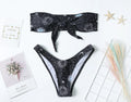 Black one-piece swimsuit with a printed bikini pattern, showing a split tube top and backless design.