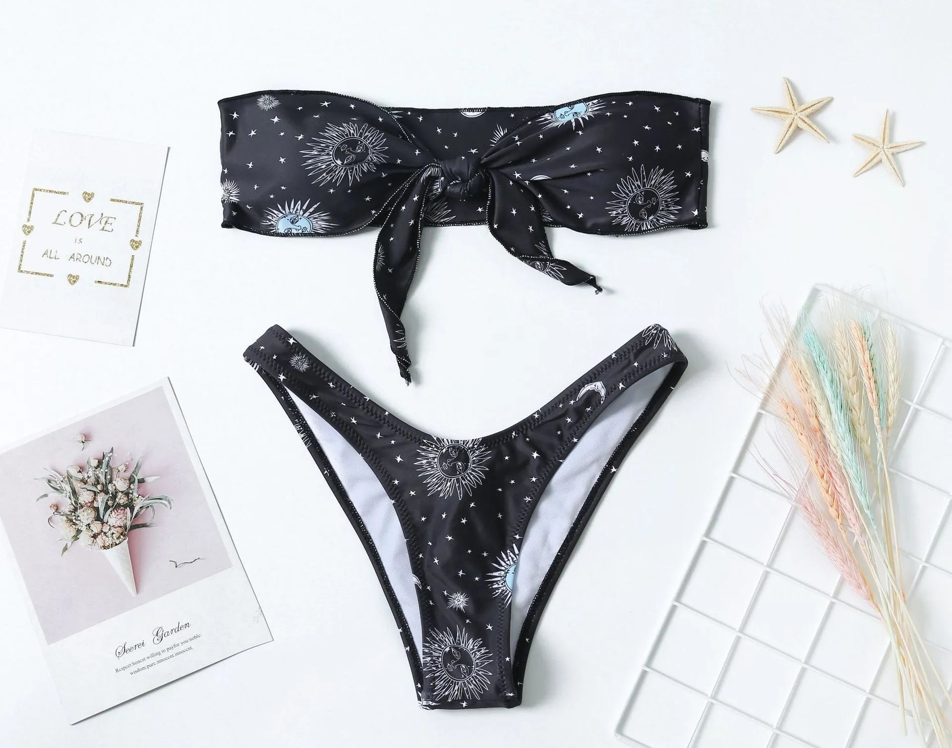 Black one-piece swimsuit with a printed bikini pattern, showing a split tube top and backless design.