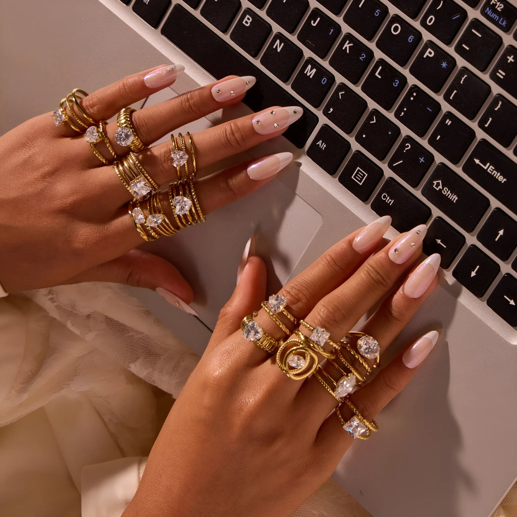 Geometric gold-coloured stainless steel ring with open mouth design on a plain background