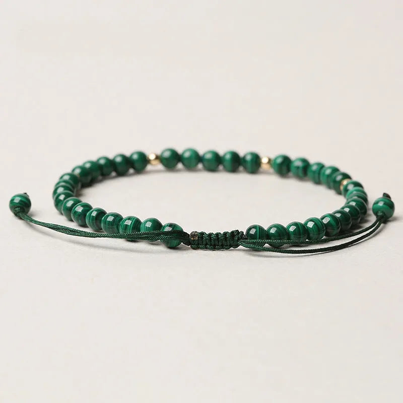 Women's malachite and gold bead bracelet with animal zodiac charm on woven strap.