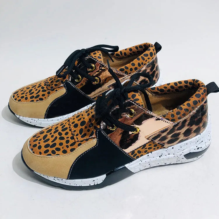 Women's black suede casual sneakers with a low wedge heel on a wooden floor.