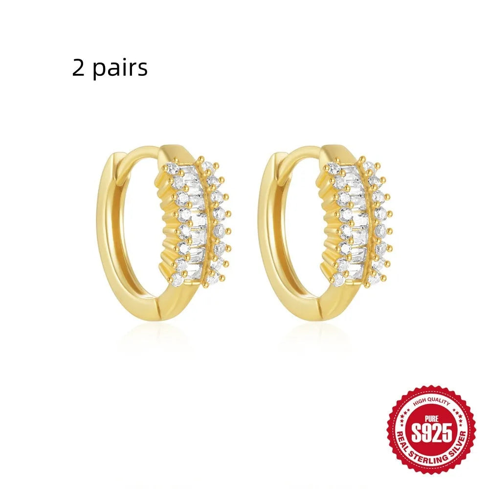 Sterling silver geometric stud earrings with small round diamond-like accents in gold and silver finishes.