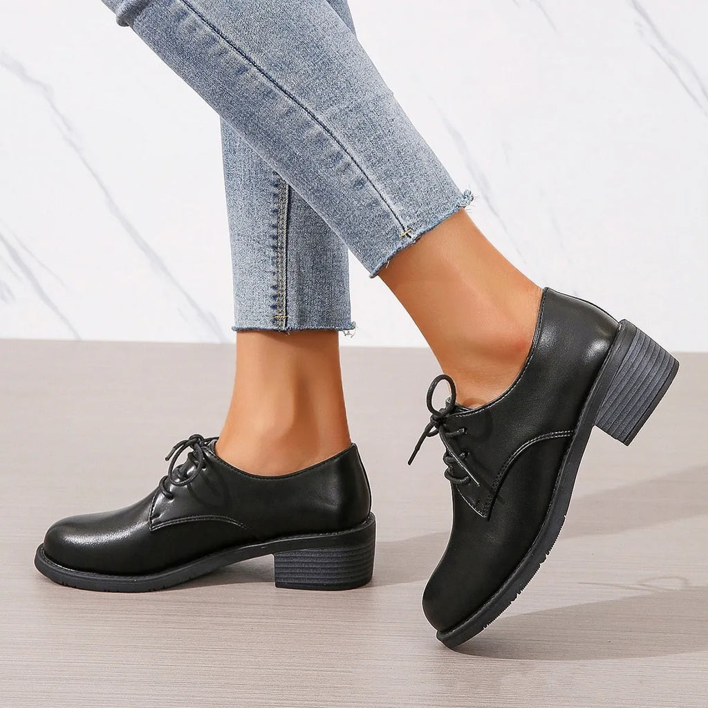 Black women's low-top work shoes with a chunky mid heel and rubber sole.