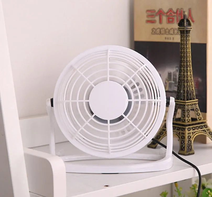 Compact black mini USB desk fan with adjustable tilt head on a wooden desk.
