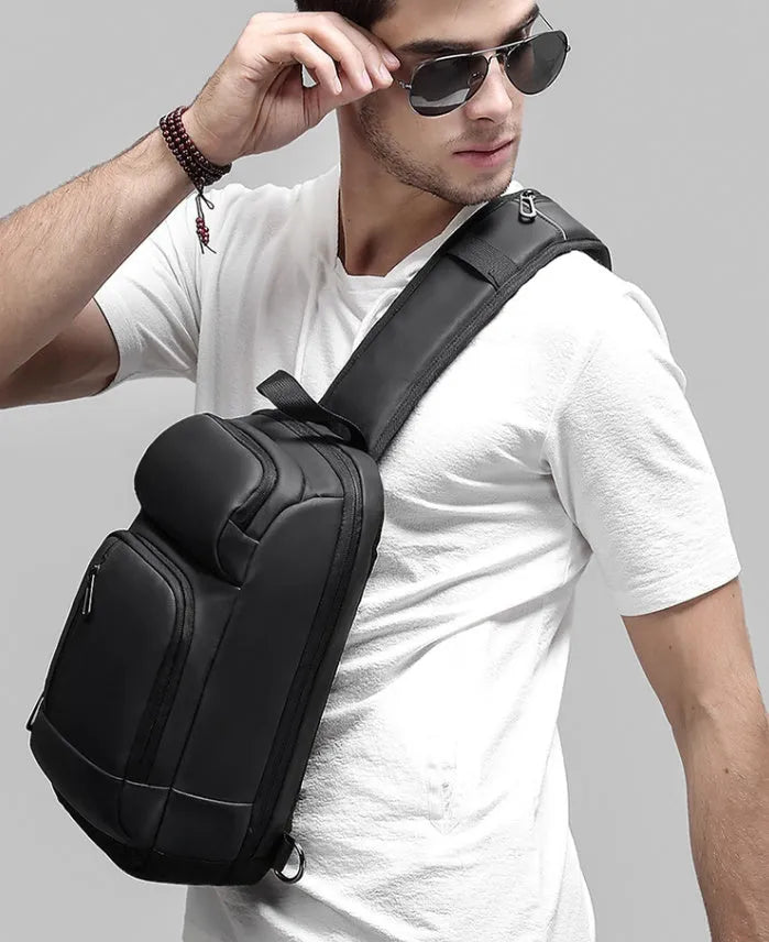 Black square vertical PVC shoulder bag showing organiser pockets and air cushion strap.