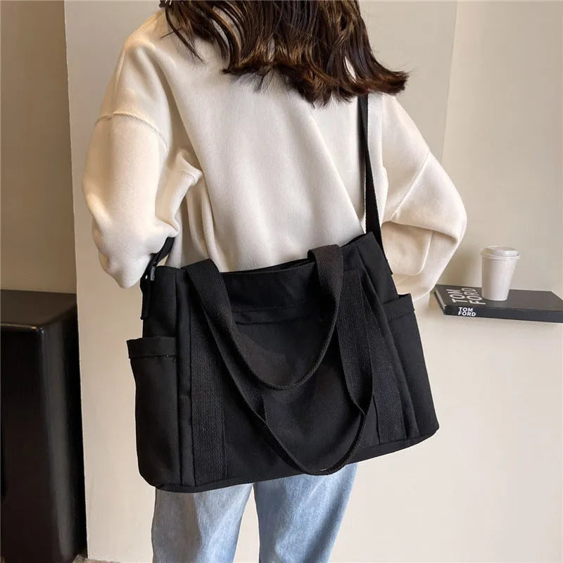 Large solid colour polyester canvas shoulder bag for women showing external pocket and strap.