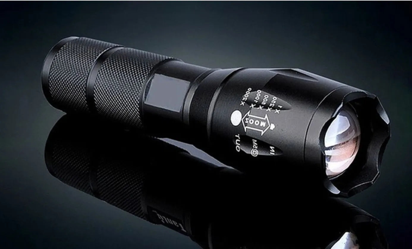 Black aluminium alloy zoomable focus LED torch with antiskid grip on a textured surface.
