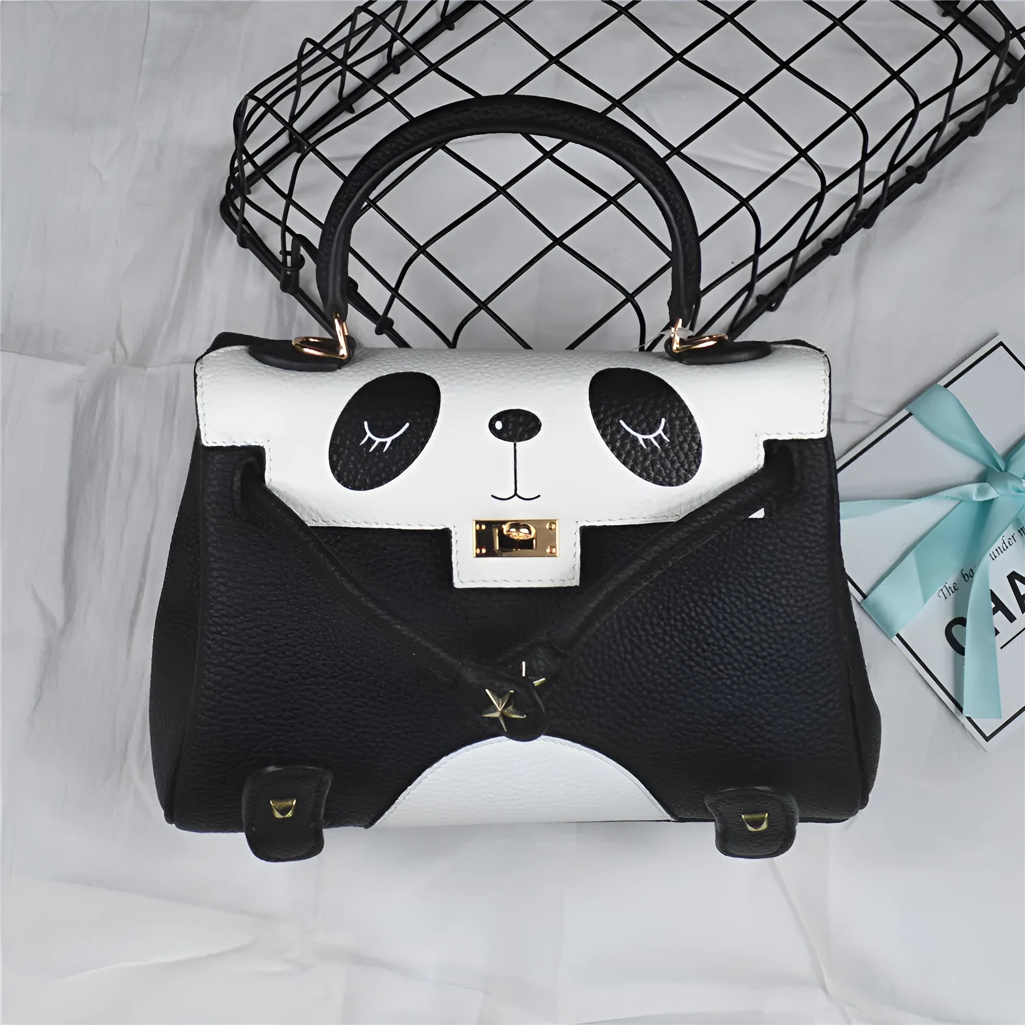 Black and white panda print on a structured horizontal square cowhide leather handbag with a trumpet detail.