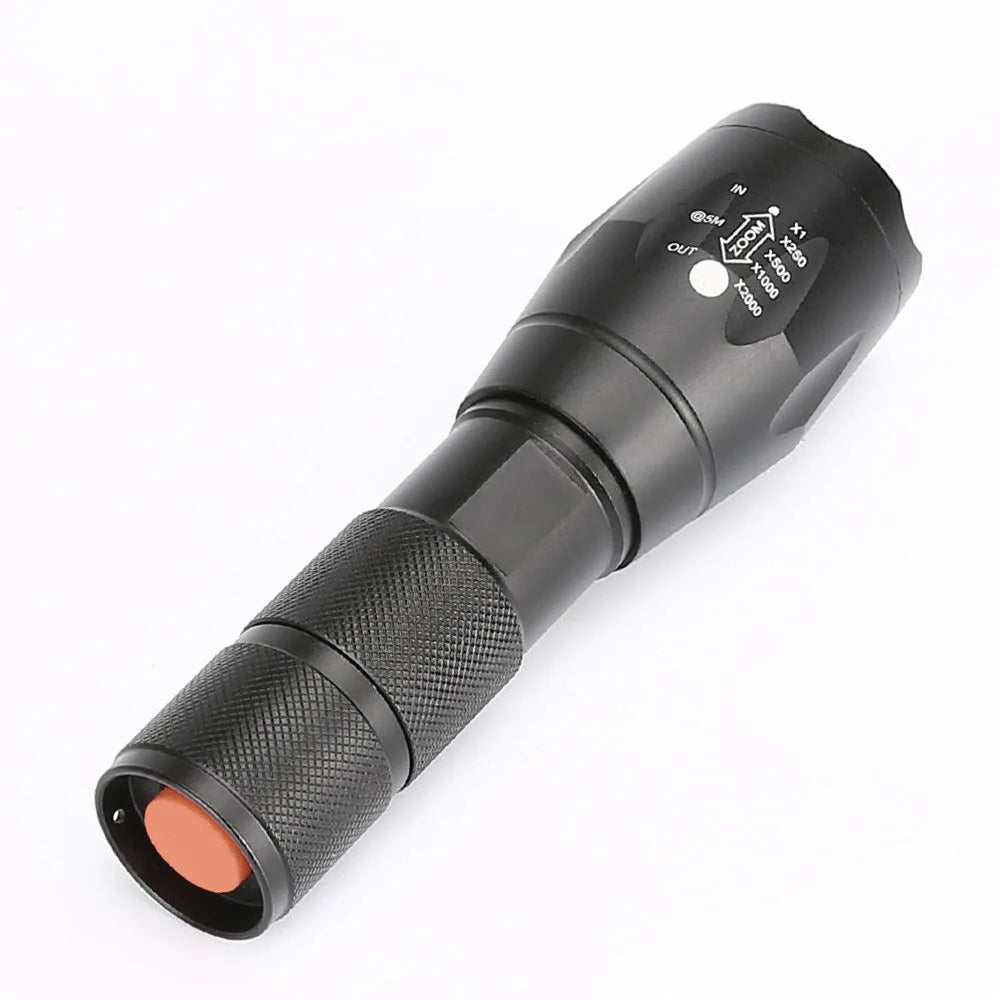 Black aluminium alloy zoomable focus LED torch with antiskid grip on a textured surface.