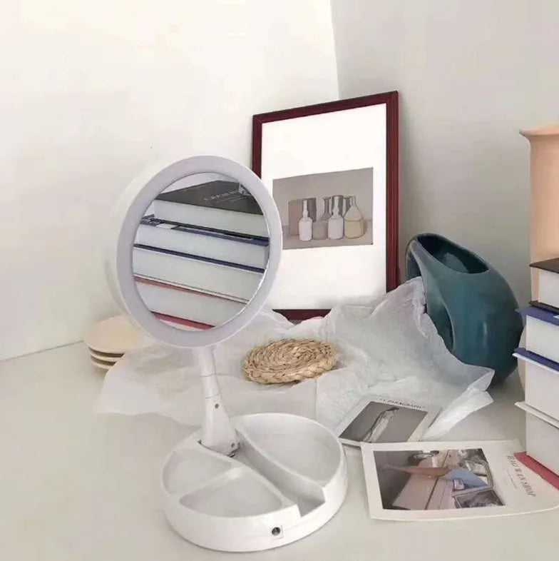 White acrylic LED vanity mirror with foldable base and storage compartment, shown unfolded on a table.