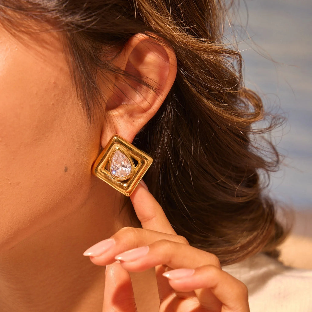 A pair of gold-coloured geometric stud earrings featuring an inlaid water drop zircon stone.