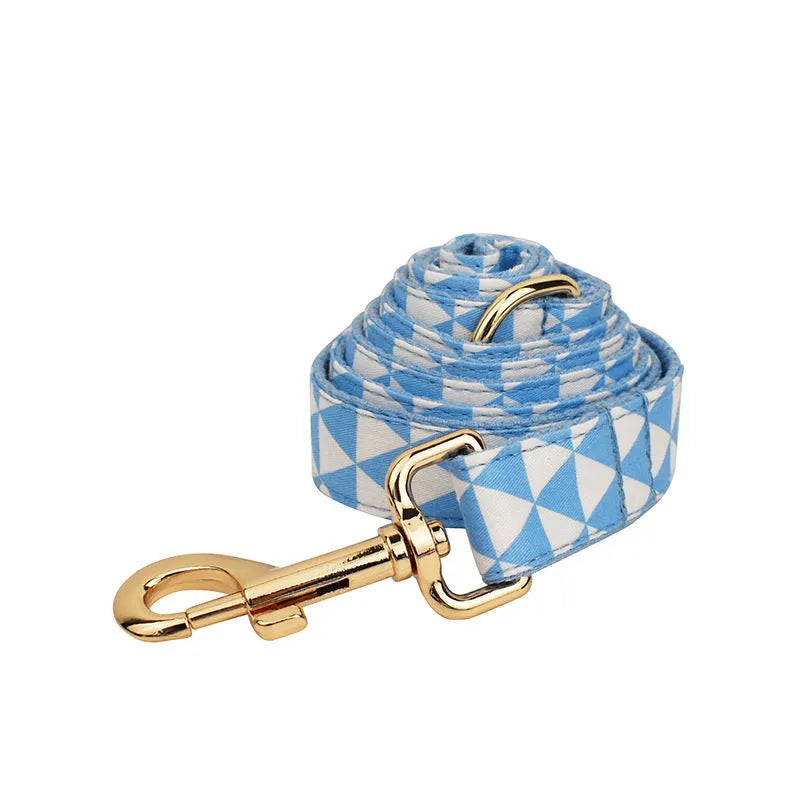 Blue cloth dog collar, lead, bow, and vest set laid out flat showing the four matching pieces.