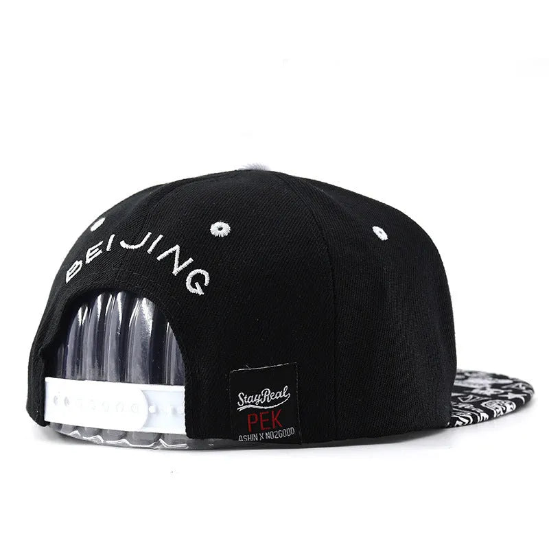 White and black adjustable cotton baseball cap with embroidered letters on the front, showing dome crown and adjustable strap.