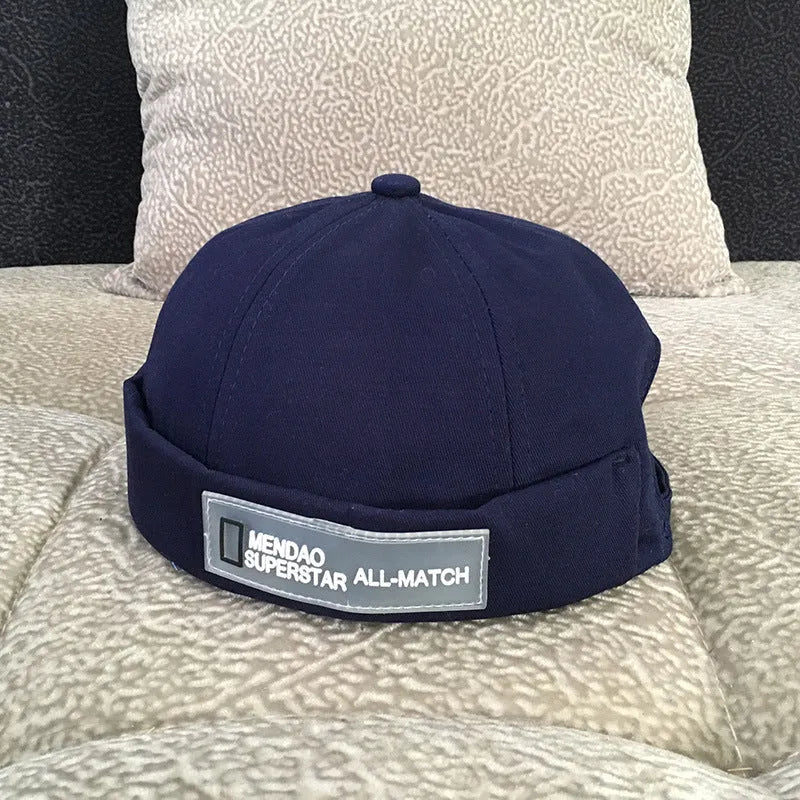 Cotton baseball cap with adjustable buckle in black showing letter pattern and rivet details