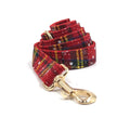 Red Christmas pet collar set with matching harness, leash, bow, and dog waste bag on cloth background