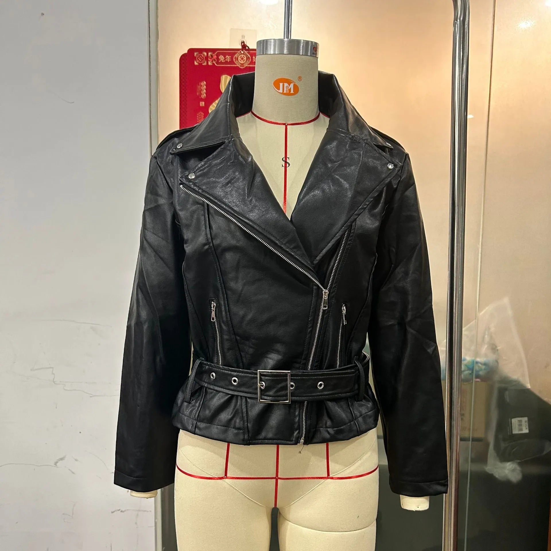 Black punk style leather jacket with a Peter Pan collar and regular sleeves on a hanger.