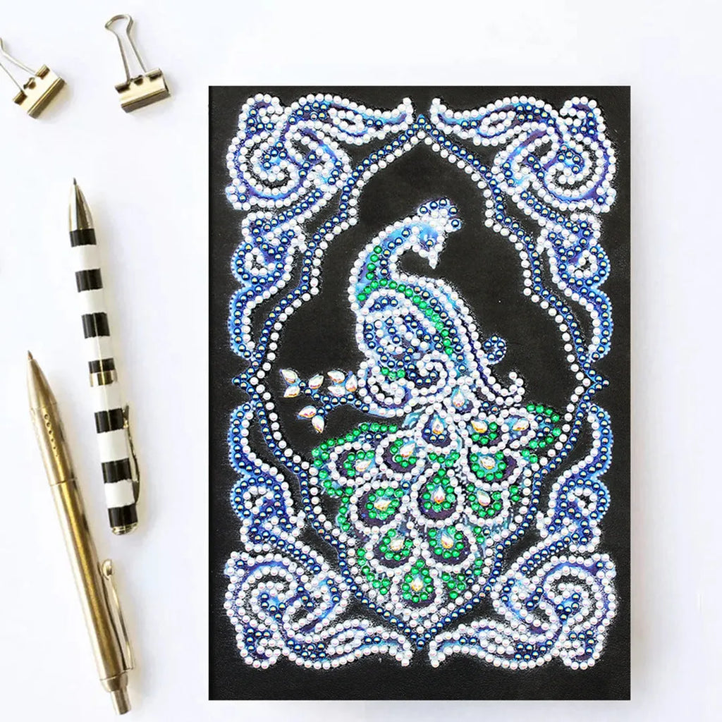 Peacock design diamond painting kit on a black A5 hardback notebook with drills and tools