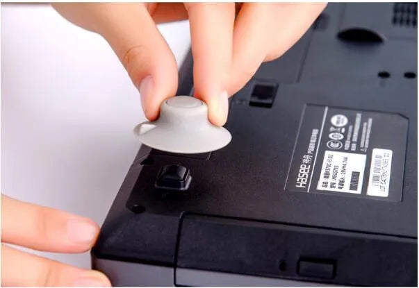 Grey laptop cooling stand with four silicone feet creating an air gap under a silver laptop.