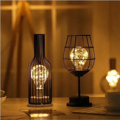 Minimalist hollow wrought iron table lamp in red wine bottle design with warm white LED light.
