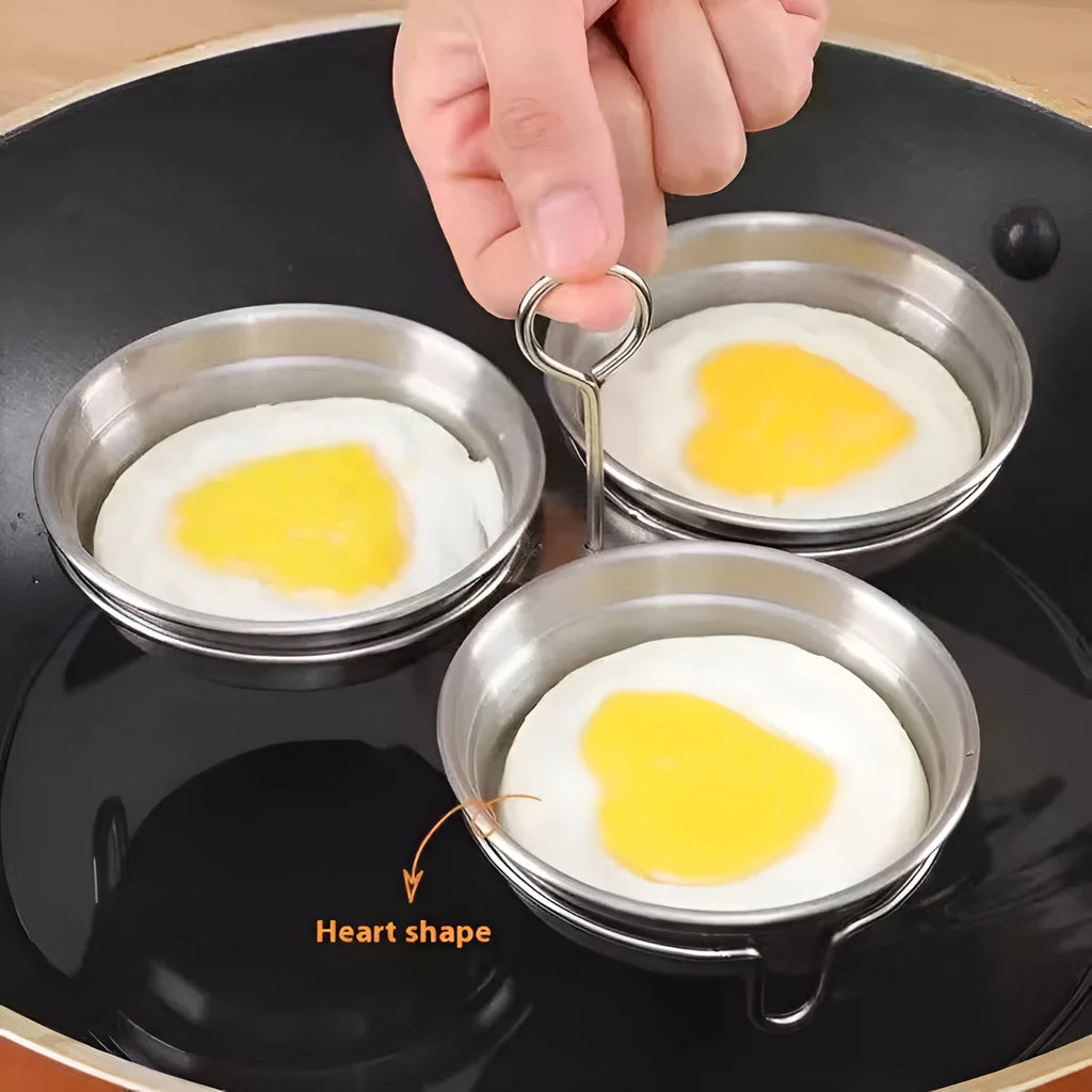 A small, round, heart-shaped stainless steel egg steamer for stovetop use.