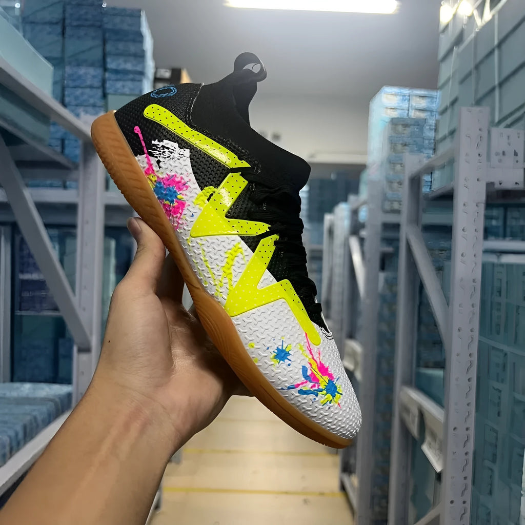 Low-top black and yellow football trainers with a spiked rubber sole and mesh detail.