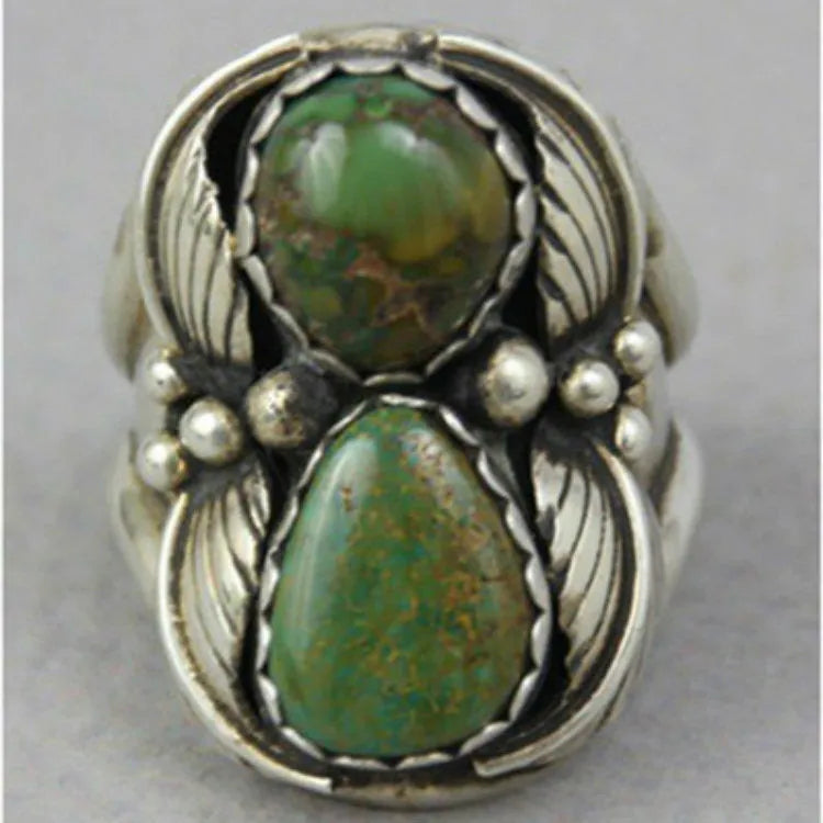 Close-up of a women's geometric turquoise alloy ring on a grey background.