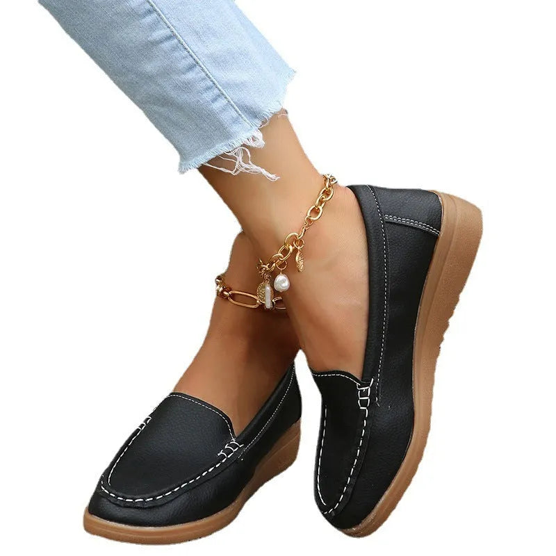 Women's black PU leather slip-on loafers with decorative stitching and a flat rubber sole.