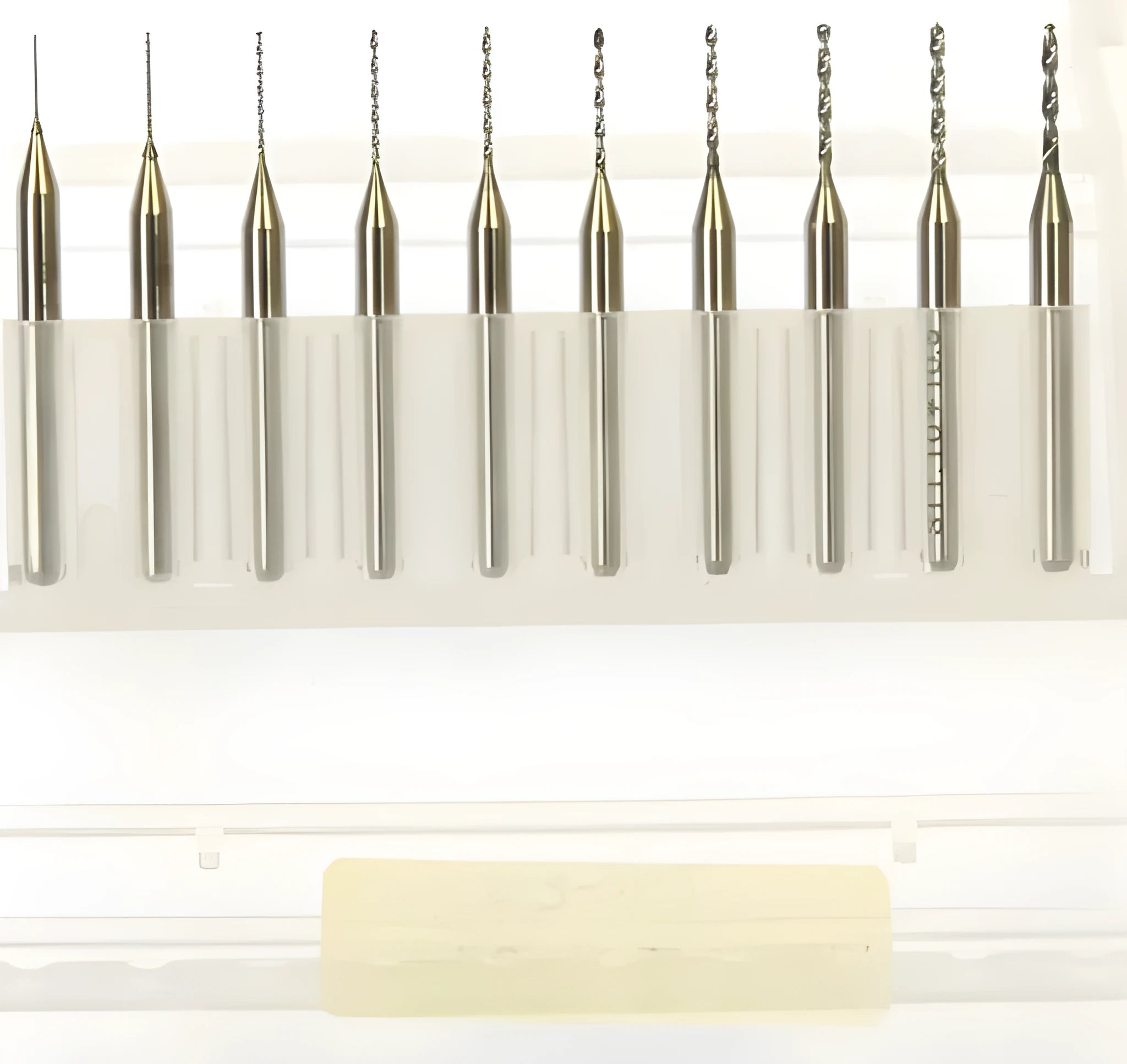 Close-up of a set of fine tungsten steel micro-engraving bits with diameters from 0.10mm to 2.00mm on a grey background.