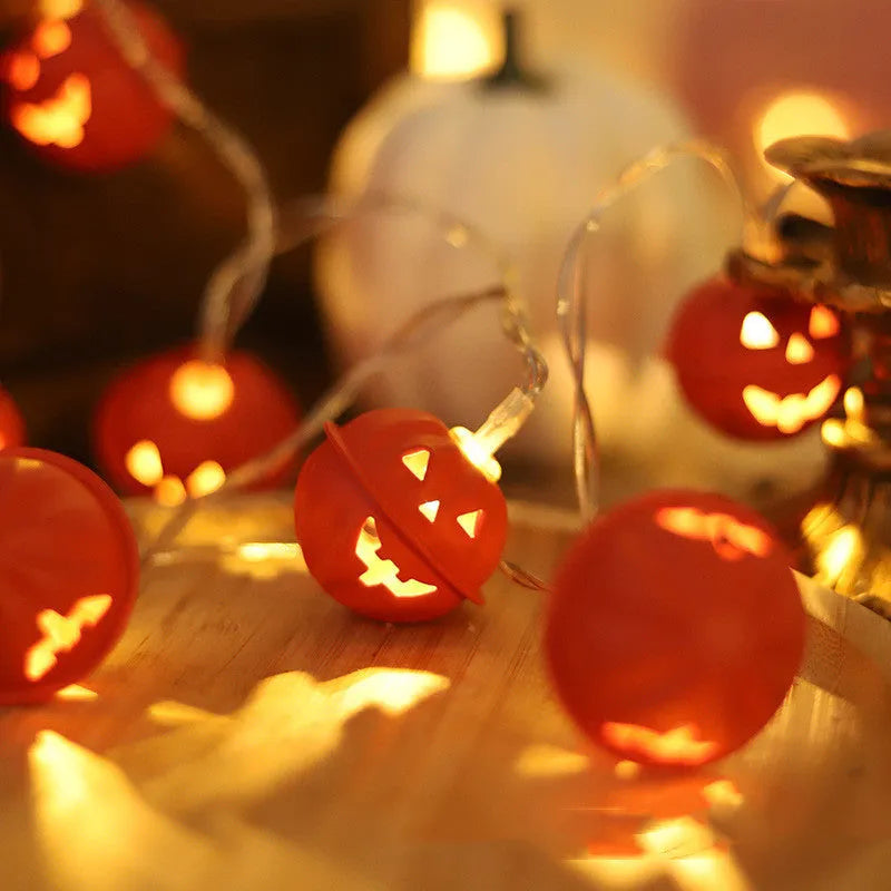 Halloween pumpkin string lights with warm white LEDs and iron pendants on a dark background