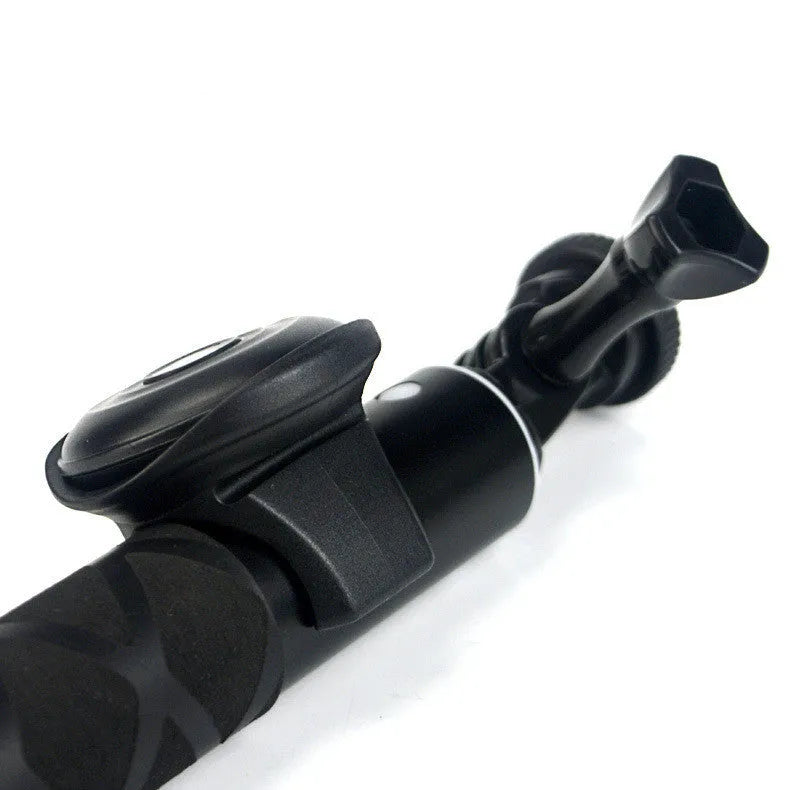 Black Bluetooth remote shutter for smartphones on a white background, shown next to a mobile phone.