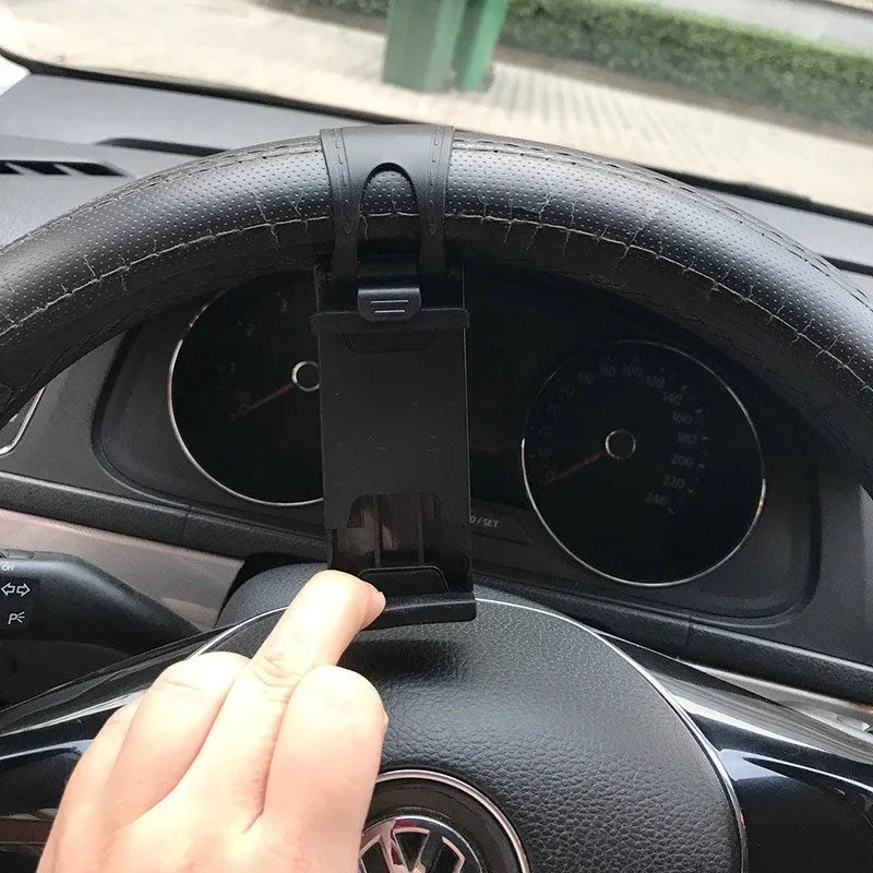 Black universal steering wheel phone holder clip mounted on a car steering wheel, holding a smartphone.