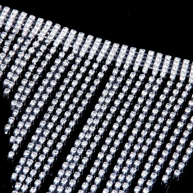 Silvery rhinestone body chain laid flat on a white surface showing metal links and clear stones