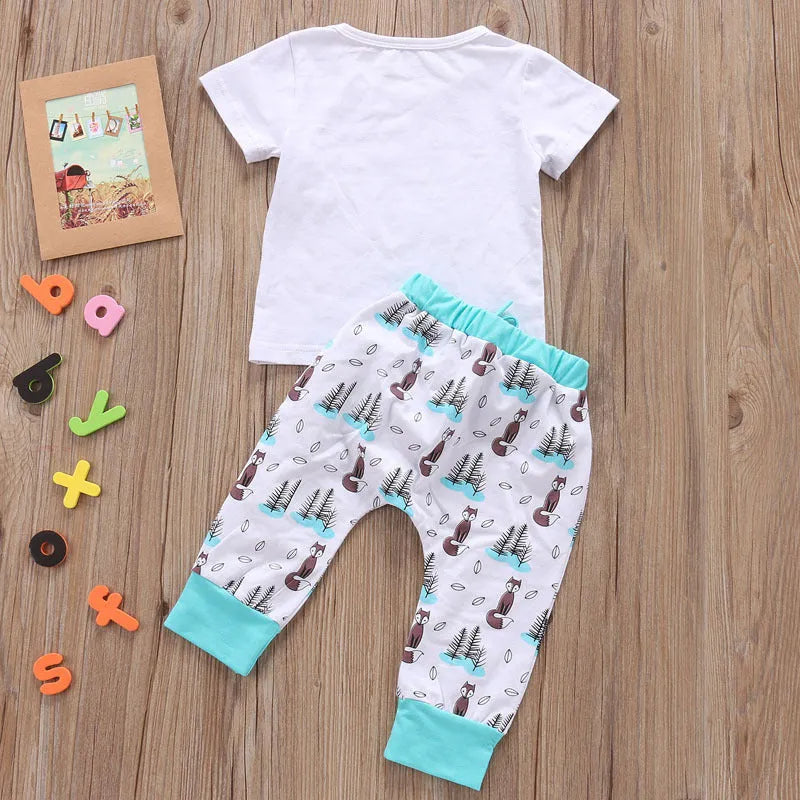 Newborn baby clothes set with white cotton T-shirt and grey pants on a soft background