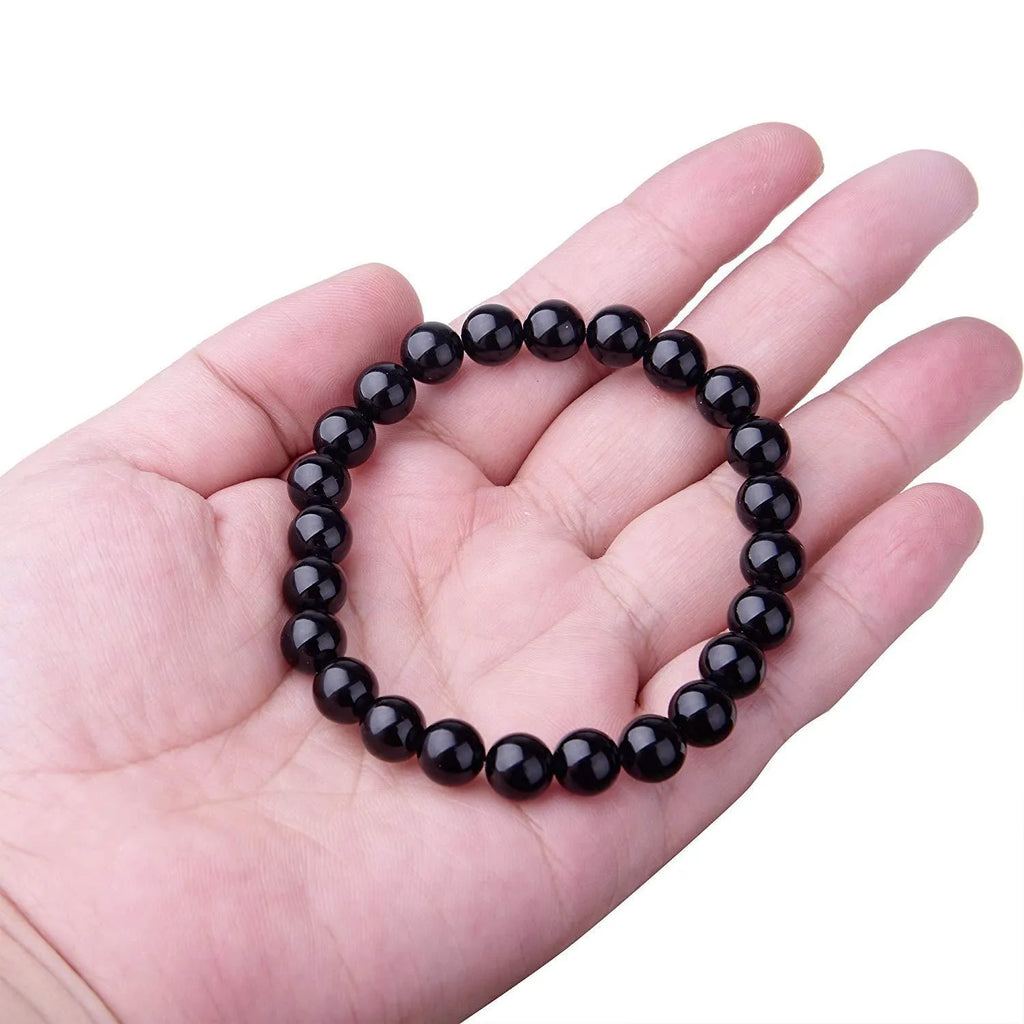 Close-up of a women's black agate bracelet with 8mm geometric beads on a black elastic cord.