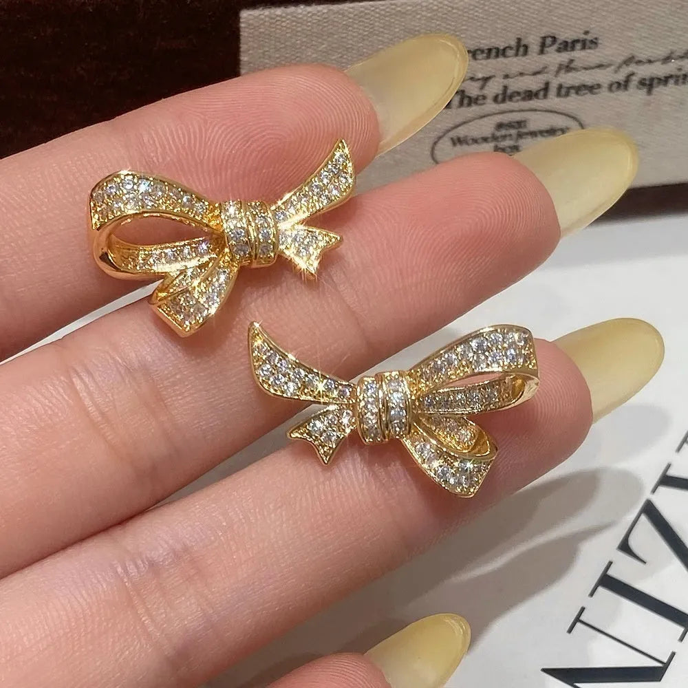 Gold miniature zircon inlaid bowknot ear stud and matching ring set on display