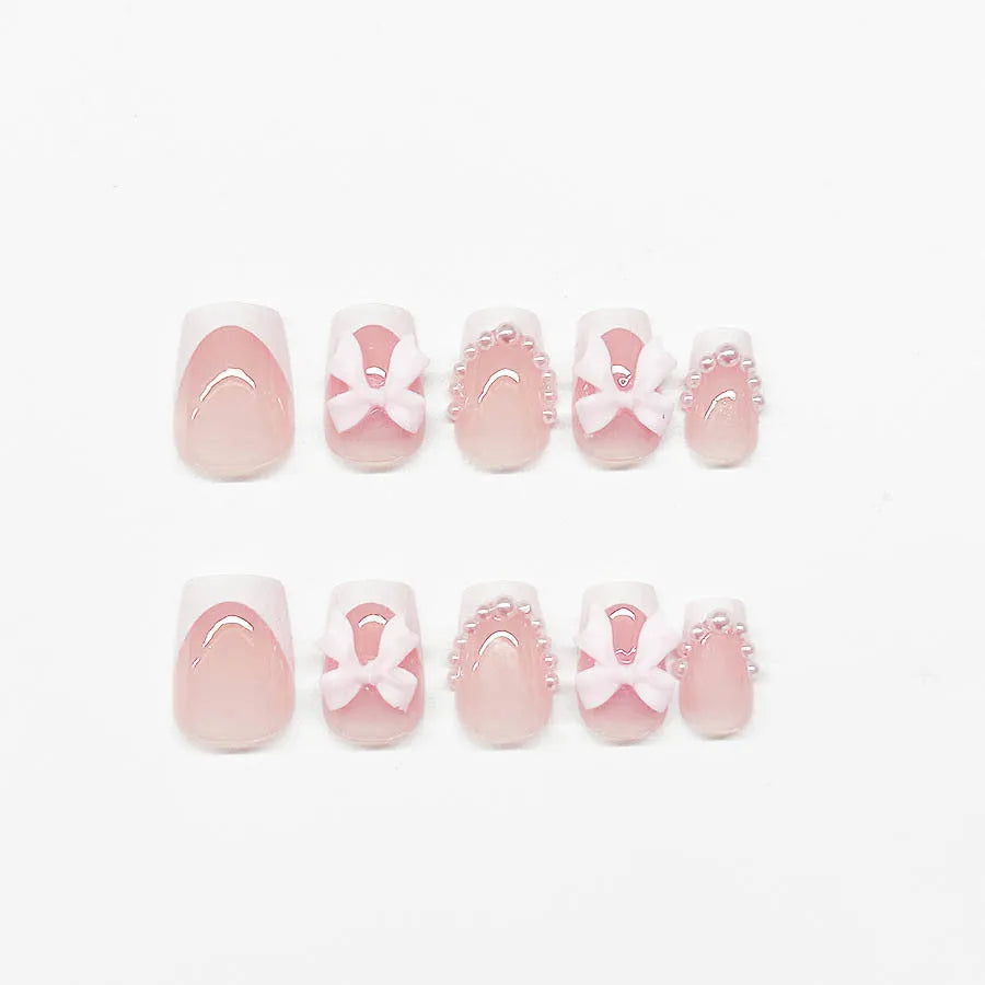 Set of short square press-on nails with white French tips, bow patterns, and tulip designs next to S274 glue bottles.