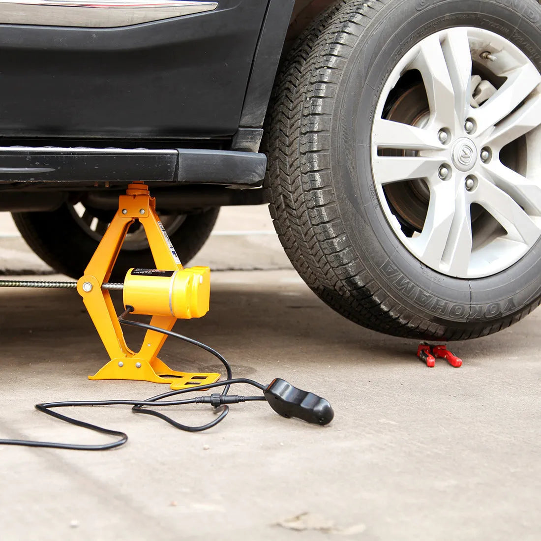 Hydraulic electric car jack kit with control box, shown stored in a vehicle boot.