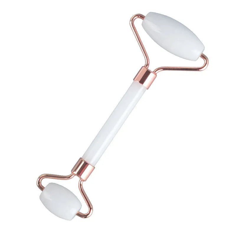 Natural white jade facial roller and gua sha scraper board set on a plain background.