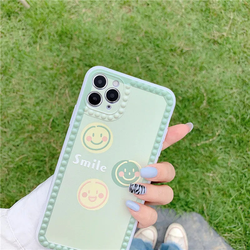 Green TPU iPhone case with geometric smiley face design and polka dot frame.