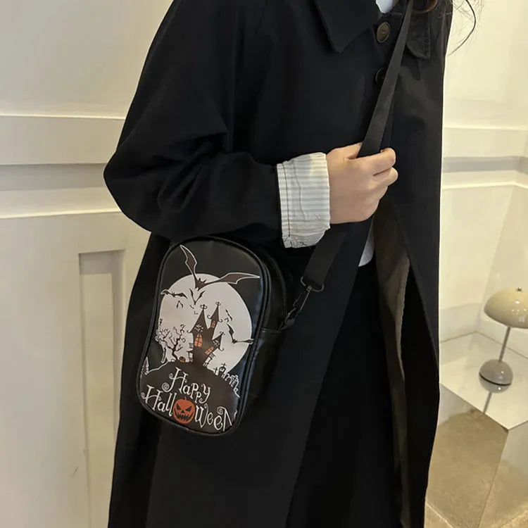 Black Halloween crossbody bag with orange pumpkin, white ghost, and black bat print, showing front zip and adjustable strap.
